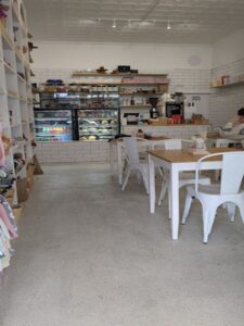 Remnscnt entrance way showing cake and sandwich cabinet with white chairs