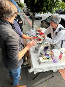 Volunteers helping pain Glen Huntly lamp posts by mixing up very bright paints