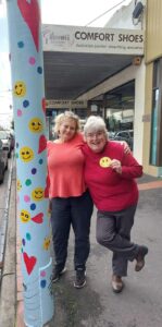 two volunteers helping paint the lamp posts along Glen Huntly road with bright colours
